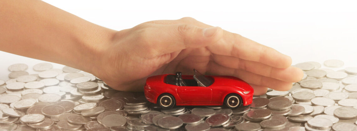 Car and house model with stack of a coins in hand