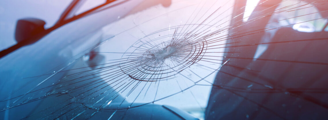 Automobile special workers remove old windscreen or windshield of a car in auto service station garage.