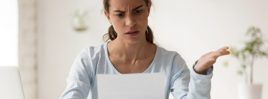 Stressed millennial mixed race woman reading paper with bad news.