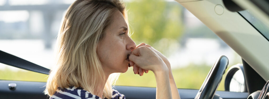 Serious anxious woman driving car. Female driver of middle age pensive sad waiting in traffic jam
