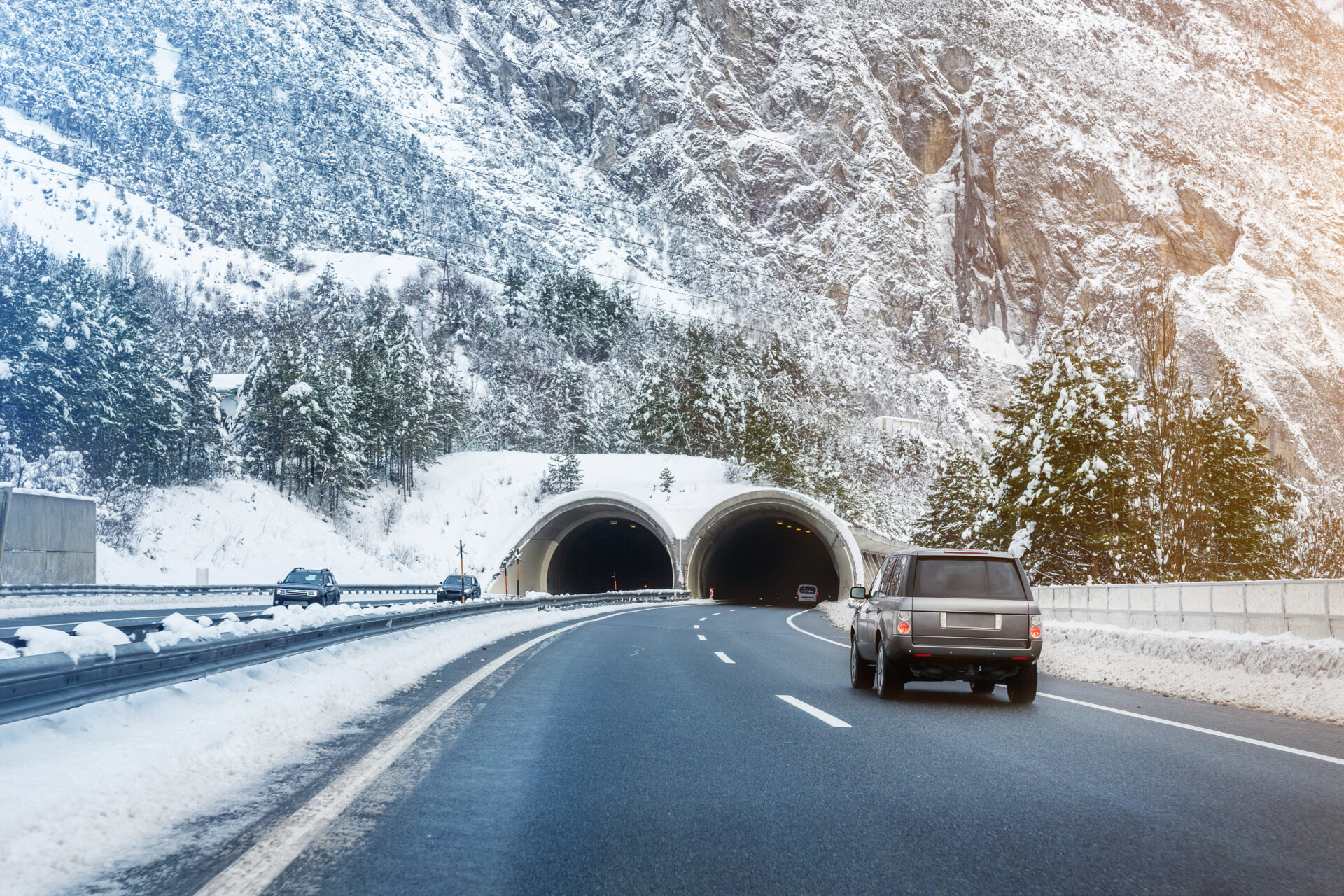Winter alpine road landscape with tunnel, forest, mountains and blue sky on background at bright cold sunny day. Car trip family travel journey. Holiday skiing vacation. scenic austrian landscape