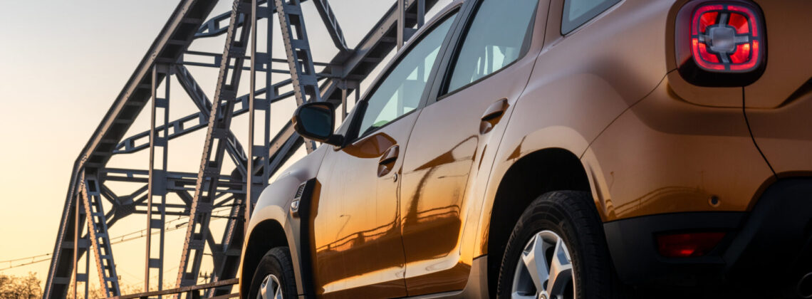Dacia Duster SUV standing on a steel truss bridge at sunset