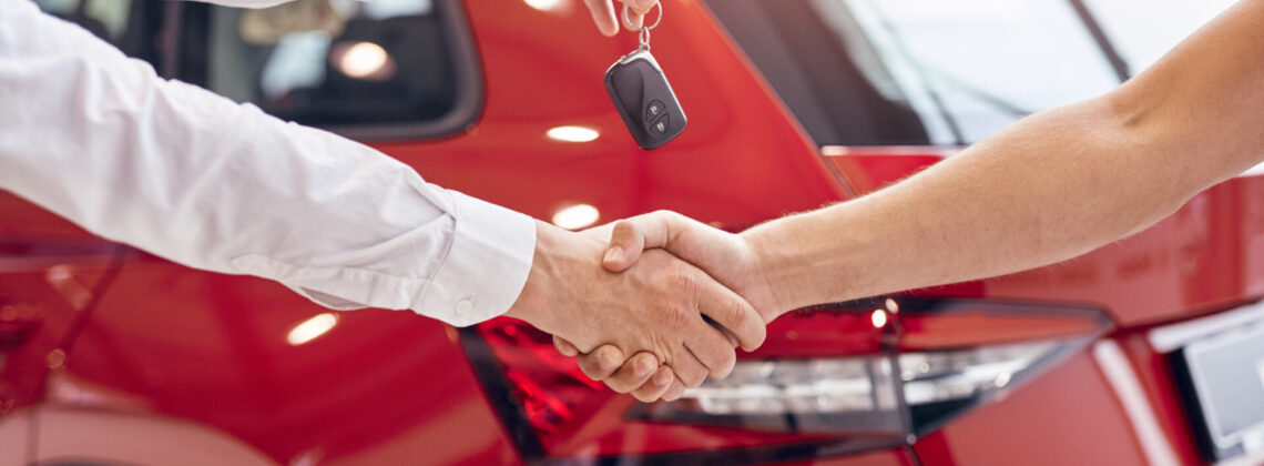 Crop dealer with car keys shaking hand of client