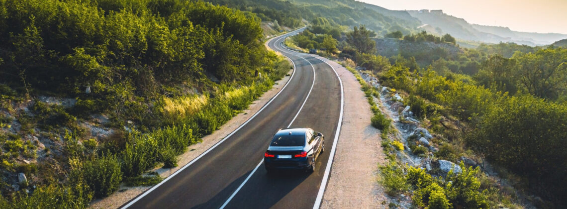 Driving on a coast road. Aerial view of a car driven on an amazi