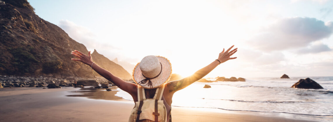 Happy woman with arms up enjoy freedom at the beach at sunset. W