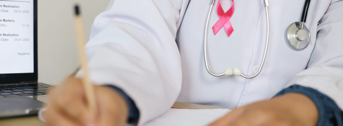 Doctor With White Coat Writting On Medical Document Wearing Pink Ribbon And Stethoscope