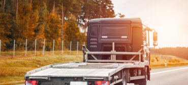 Laweta jadąca pustą platformą po drodze w otoczeniu jesiennych drzew